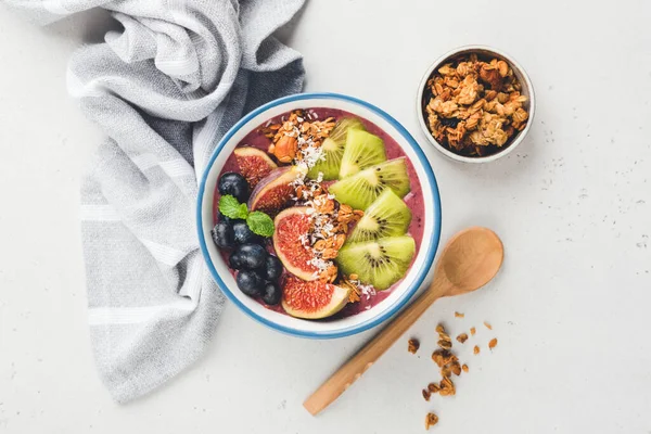 Healthy vegan smoothie bowl with fruits and granola topping. Top view. Acai smoothie bowl