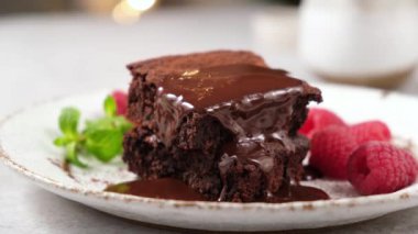 Çatalla browni yemek. Çikolatalı pasta, krema ve ahududu dilimleri.