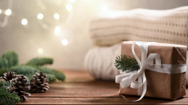 木製のテーブルの上にギフトボックス セーター モミの木やクリスマスライト付きのクリスマスの背景 デザインまたはテキストのコピースペース — ストック動画