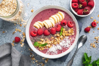 Meyve, granola ve çekirdekli mor smoothie kasesi.