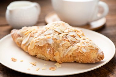 Beyaz tabakta bademli kruvasan.