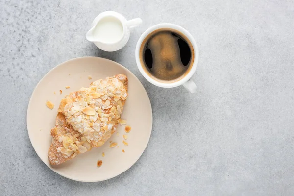 Zwarte koffie en amandelcroissant — Stockfoto