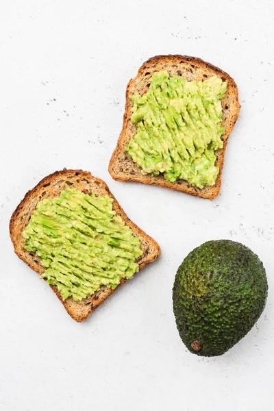 Whole grain toast with mashed avocado isolated on concrete background, top view, copy space