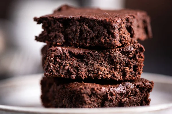 Dark chocolate brownies. Three delicious square pieces of fudgy chocolate brownies on a plate, closeup view