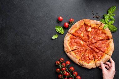Bir dilim pepperonili pizza. Siyah taş beton zemin, metin ya da tasarım elementleri için kopyalama alanı olan üst görünüm. Sağlıksız fast food konsepti yemek