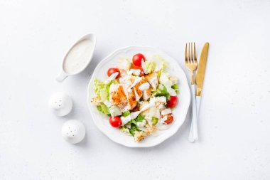 Izgara tavuk göğsü, kiraz domatesli Sezar salatası ve beyaz tabakta beyaz beton kaplama sos. Kopyalama alanı olan üst görünüm. Lezzetli, sağlıklı, ünlü Sezar salatası tarzı