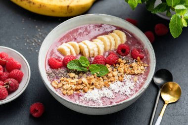Ahududu, muz, chia tohumu, hindistancevizi ve tahıl gevreğiyle süper yemek kasesi. Sağlıklı arınma kilo kaybı öğün meyve pembesi mor smoothie