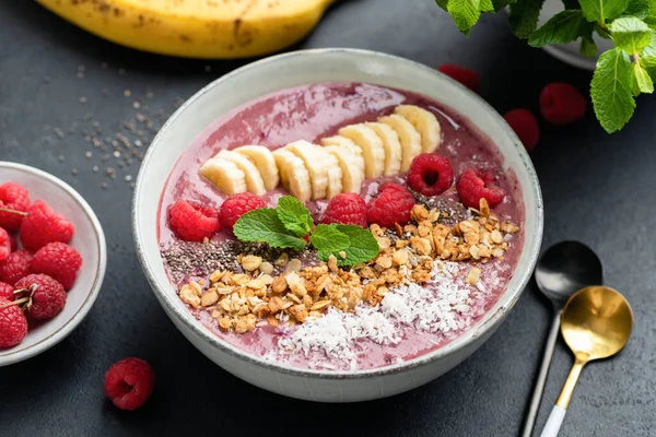 Superfood smoothie bowl with raspberry, banana, chia seeds, coconut and granola. Healthy detox weight loss meal fruit pink purple smoothie