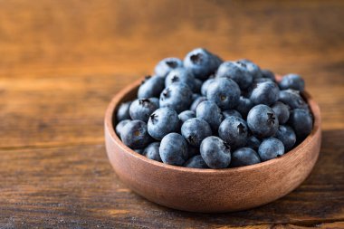 Eski ahşap masa arkasındaki ahşap kasede bulunan organik yaban mersini. Metin ve tasarım için kopyalama alanı var.