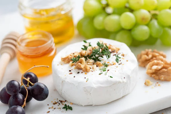 Сыр Camembert подается с грецкими орехами, виноградом и медом — стоковое фото