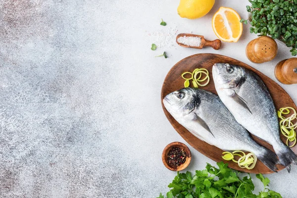 Pescado dorado sin cocer en bandeja de madera e ingredientes para cocinar —  Fotos de Stock