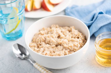 Beyaz kasede pişirilmiş yulaf lapası, diyet için sağlıklı kahvaltı yemeği, fitness menüsü, temiz yemek yaşam tarzı.