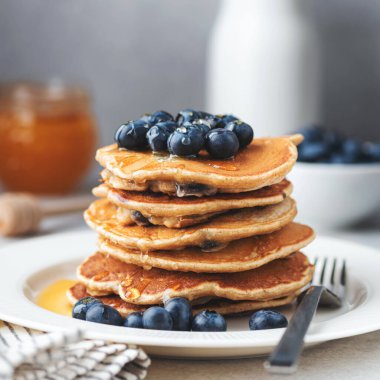 Beyaz tabakta yaban mersinli krep ve şurup yığını, yakın çekim manzarası. Tatlı kahvaltı yemeği. Kare bileşimi
