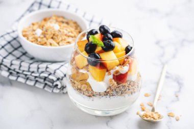 Tahıllı yoğurt ve cam kavanozda meyveler.