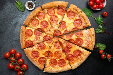 Siyah beton arka planda dilimlenmiş Pepperoni pizza.