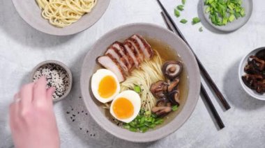 Asya eriştesi çorbası. Domuz eti ve yumurtalı, susam tohumuyla süslenmiş Ramen kasesi.