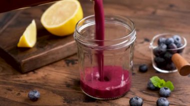 Cam bir kavanoza yaban mersini kokteyli dökülüyor. Kalın mor yaban mersinli acai smoothie, vitamin ve antioksidan açısından zengin. Süper yiyecek içeceği