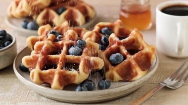 Belçika wafflelarında yavaş çekimde elek şekeri. Tatlı kahvaltı yemekleri, çıtır çıtır waffle 'ların yakın görüntüsü.