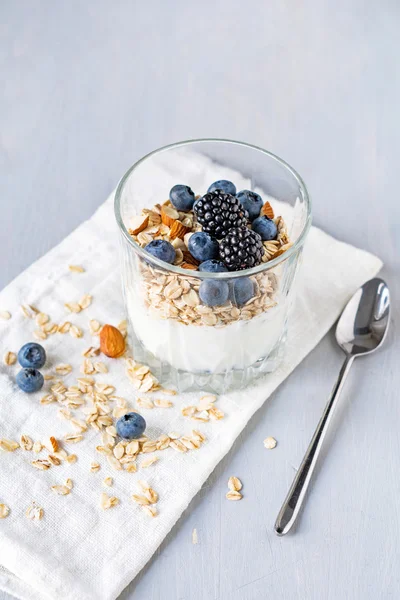 Iogurte com muesli e bagas frescas em vidro na mesa. Comida saudável para pequeno-almoço — Fotografia de Stock