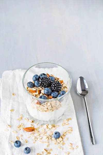 Iogurte com muesli e bagas frescas em vidro na mesa. Comida saudável para pequeno-almoço — Fotografia de Stock