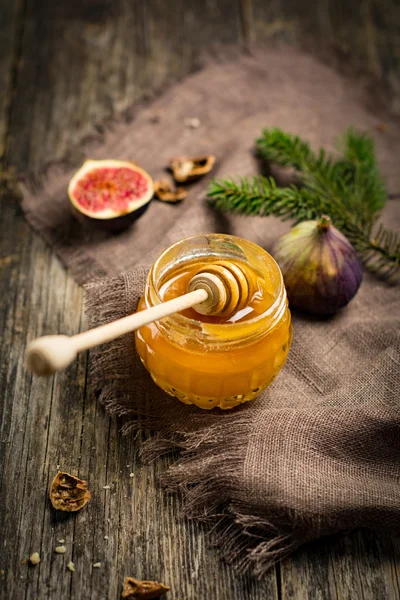 Miel en tarro, frutas y frutos secos sobre fondo de madera —  Fotos de Stock