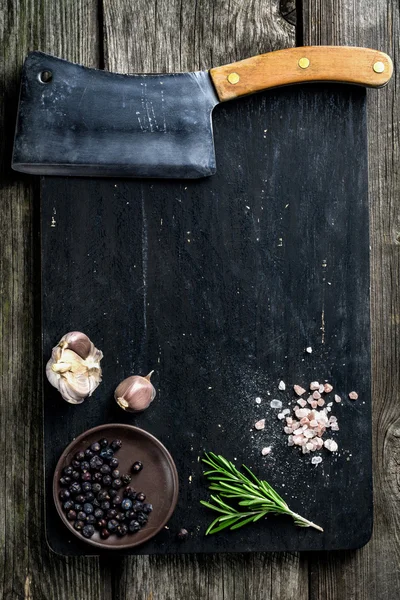 Doğrama tahtası, et satır ve çeşniler koyu ahşap arka plan üzerinde