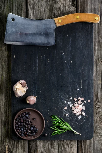 Tábua de corte, cutelo de carne e condimentos em fundo de madeira escura — Fotografia de Stock