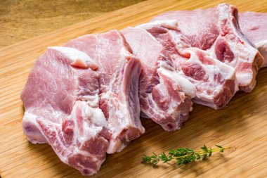 Çiğ et, domuz pirzolası ahşap kesme tahtası üzerinde