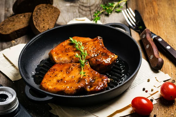 Chuleta de cerdo BBQ con glaseado dulce y tomillo, servida en sartén de hierro — Foto de Stock