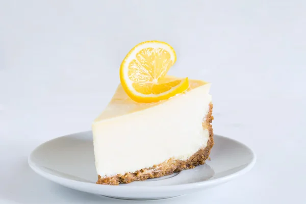 Лимонный чизкейк на белой тарелке, изолированный — стоковое фото