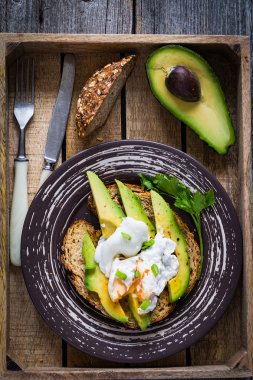 Avokado, haşlanmış yumurta ve kepekli ekmek. Antika ahşap tepsi üzerinde Odaya Servis Kahvaltı. Üstten Görünüm