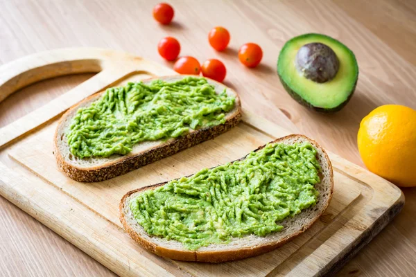 Toast mit pürierter Avocado auf Holzschneidebrett — Stockfoto