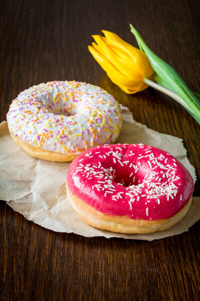 Пончики и цветок тюльпана на коричневом фоне
