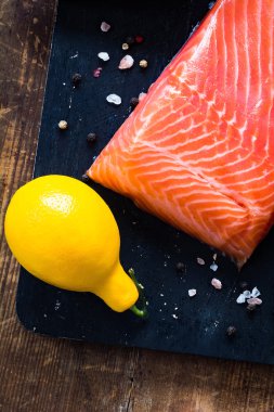 Somon fileto ve limon siyah kesme tahtası üzerinde