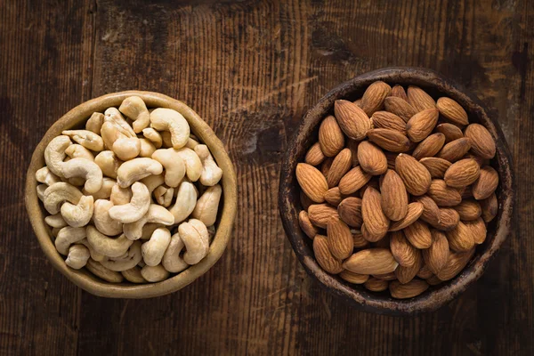 Gesunde Lebensmittel: Schüssel mit Cashewnüssen und Mandeln auf Holztisch — Stockfoto