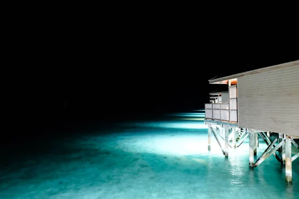 Lights under the house in the sea at night. Beach background.