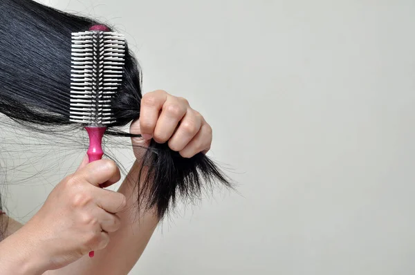 The woman is combing her long hair