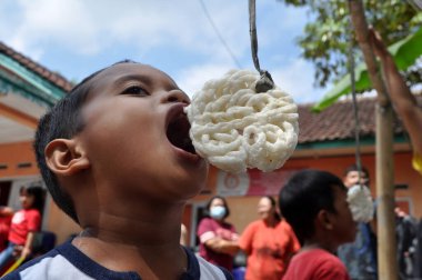 Ciamis, Endonezya - 17 Ağustos 2021: Endonezya Cumhuriyeti, Ciamis, Batı Java-Endonezya 'nın bağımsızlık günü kutlamalarında çocuklar kraker yeme yarışmasına katılıyor