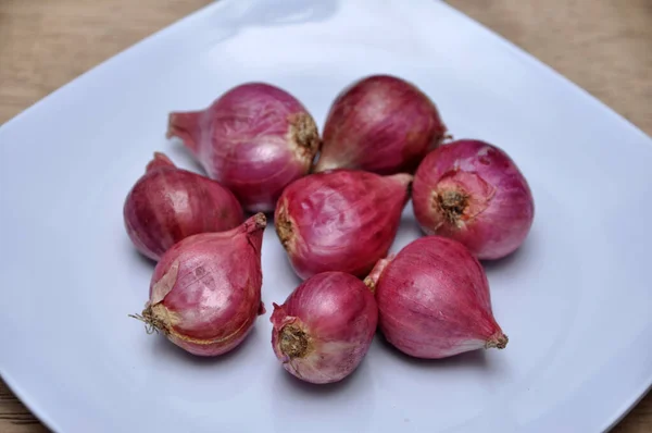 Mutfaktaki Ahşap Masada Beyaz Bir Tabakta Soğanlar — Stok fotoğraf