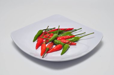 Beyaz bir arka plan stüdyo çekiminde beyaz tabakta kırmızı biber.