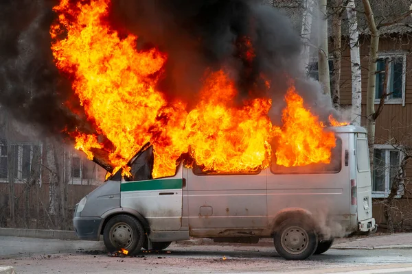 Burning old minibus on the street. Fire in a car, ignition of electrical wiring.