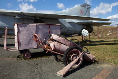 Aerodrome maintenance technique. Old airfield equipment sits next to an old jet fighter.