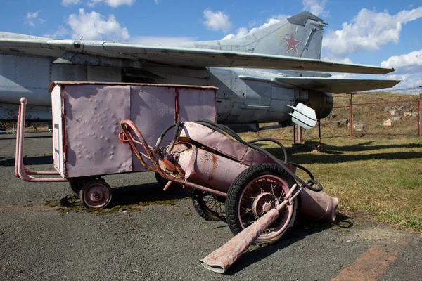 飛行場のメンテナンス技術 古い飛行場の機器は 古いジェット戦闘機の隣に座っている — ストック写真