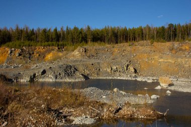 Urallar 'da büyük bir kariyerin güzelliği. Çam ağaçları kayalık bir taş ocağının ocaklarında, maden ocaklarında ve dipteki suda yetişir. Kırmızımsı taşlar