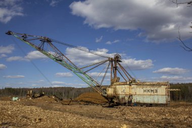 Yerden yükselen yürüyen bir kazıcı. Bir taş ocağının arka planında dev bir kazıcı dondu.
