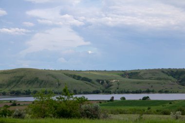 Sakin geniş nehir sularını sabah gökyüzünün altında taşır. Tepeler, ağaçlar ve Rusya 'da bir nehir manzarası