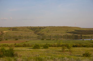 Sakin geniş nehir sularını sabah gökyüzünün altında taşır. Tepeler, ağaçlar ve Rusya 'da bir nehir manzarası