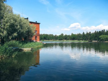 Eski kırmızı tuğla bina ve mavi gökyüzü ve beyaz bulutları olan küçük bir tekne..