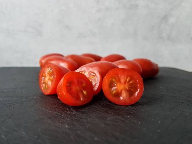 Kesilmemiş erik domatesleri siyah bir kesim tahtasının üzerinde.