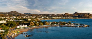Rodos 'taki Faliraki tatil köyünün panoraması. Deniz, sahil ve çevresindeki tepeler.